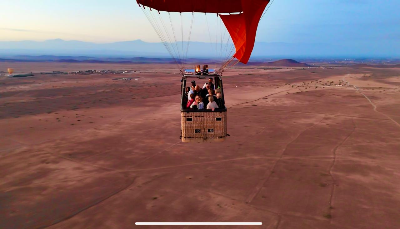 Passengers enjoying sunrise panorama from hot air balloon basket