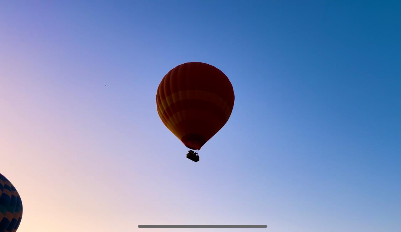 Single hot air balloon floating high in a clear dawn sky during a Marrakech balloon flight