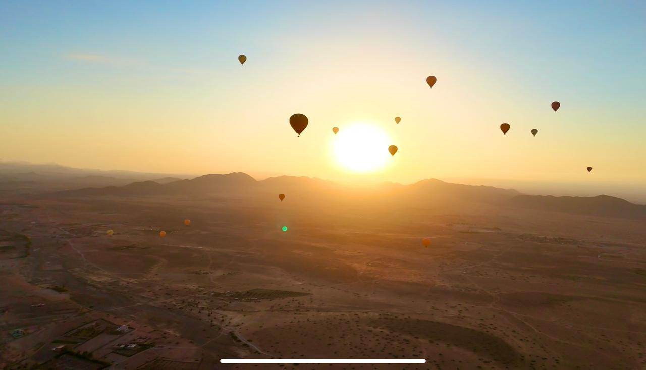 Silhouettes of hot air balloons floating against the sunrise horizon near Marrakech