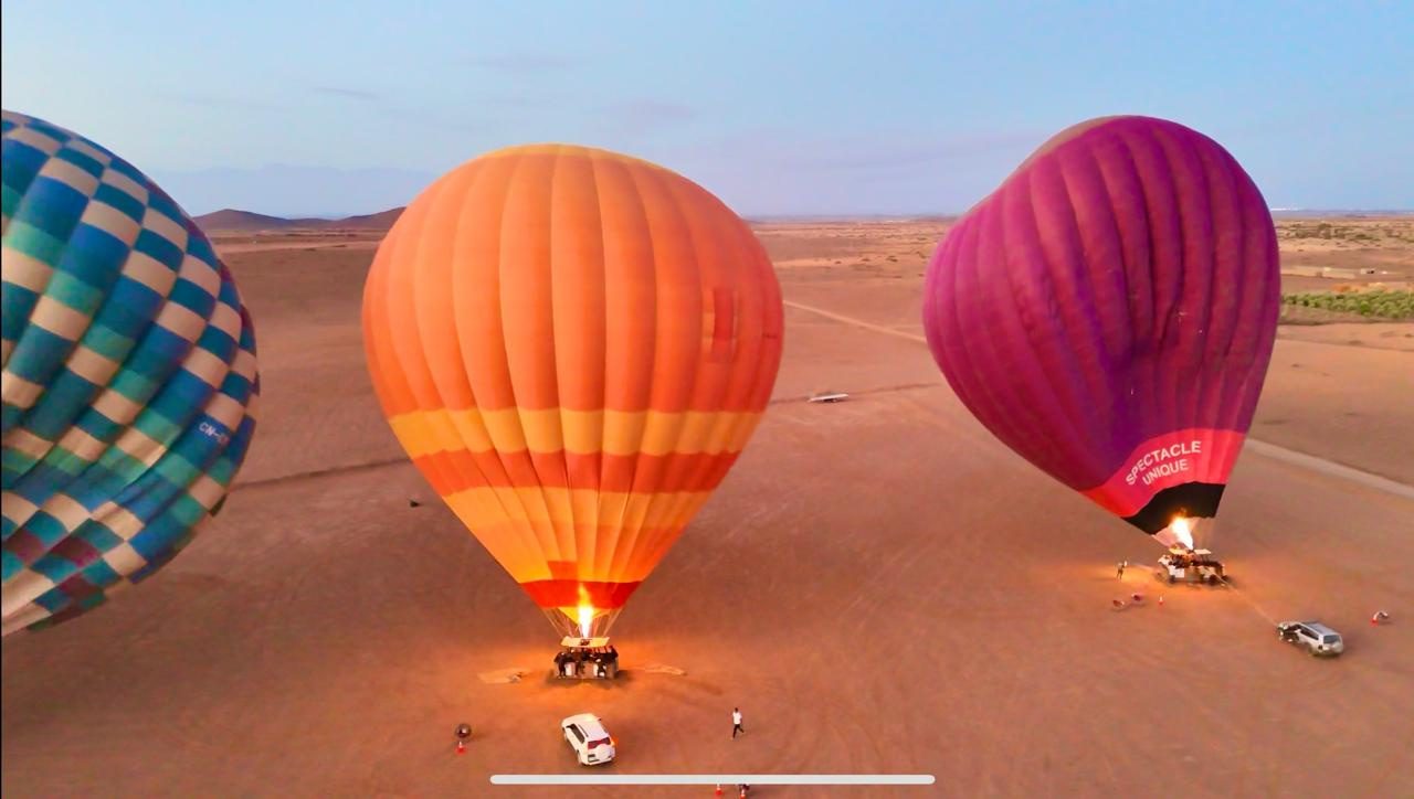 Aerial view of three colorful hot air balloons inflated on an open launch field near Marrakech