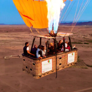 Bright burner flame above a wicker passenger basket during a hot air balloon flight near Marrakech