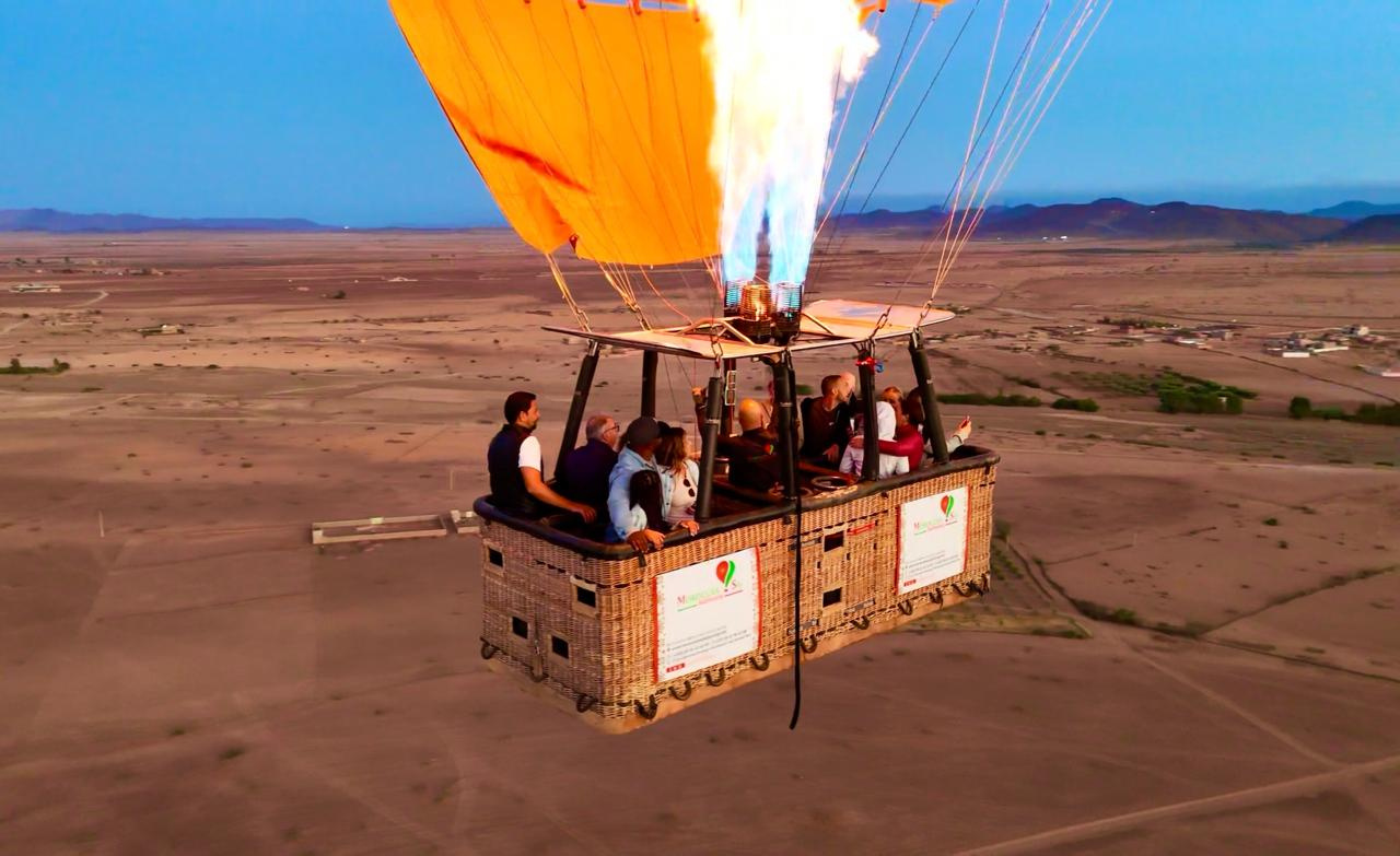 Bright burner flame above a wicker passenger basket during a hot air balloon flight near Marrakech