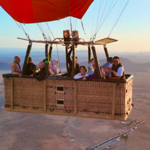 Large hot air balloon basket with a group of passengers high above roads and countryside near Marrakech