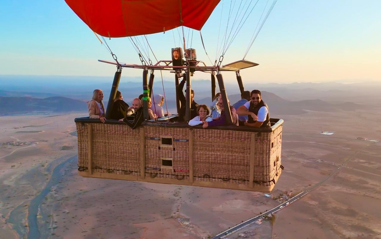 Large hot air balloon basket with a group of passengers high above roads and countryside near Marrakech