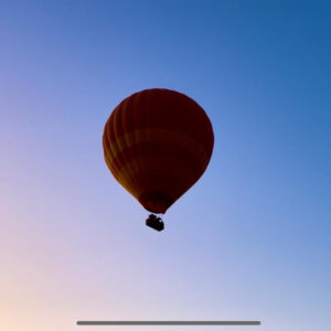 Single hot air balloon floating high in a clear dawn sky during a Marrakech balloon flight
